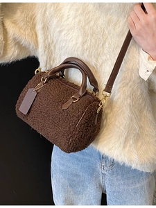 Deep brown plush Boston bag with leather handles shown as a crossbody on a model