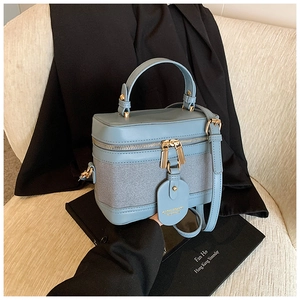 Top view of a light blue leather and canvas bucket bag with gold hardware on a sofa