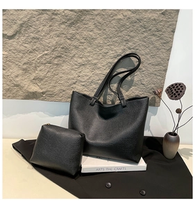 Close-up of black pebble leather tote bag set with matching zippered clutch organizer