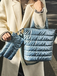 Light blue metallic quilted tote bag with matching pouch shown on beige cashmere coat