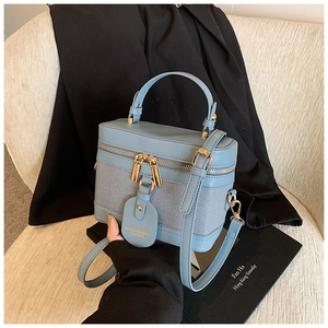 Detail view of the light blue bucket bag with gold zippers and stitched leather texture