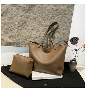 Close-up of brown lychee texture tote bag and matching pouch set on art books