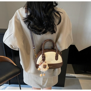 Model view of two-tone brown Boston bag with shoulder strap and sheep charm