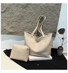 Macro shot of beige lychee texture leather tote and matching small zippered pouch set