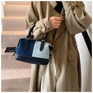 Detailed close-up of contrast denim patchwork Boston bag with leather handles and gold studs