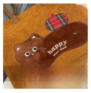 Detail of brown corduroy tote bag showing cat embroidery and plaid patch texture