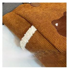 Close-up of brown corduroy bag with soft sherpa detail and cute bear patch