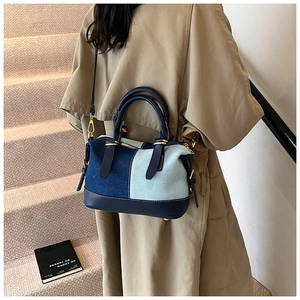 Detailed back view of a denim patchwork Boston bag worn with a beige trench coat
