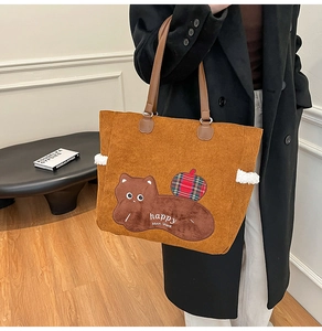 Detail of corduroy tote bag featuring cartoon animal embroidery and leather handle
