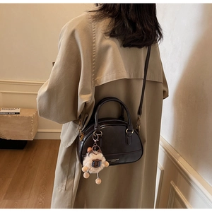 Detail of vintage dark brown shell bag with cute plush sheep pendant and adjustable strap