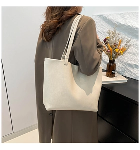 Detail of soft cream white pebble leather tote bag shown worn on a shoulder