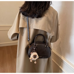 Detail of a dark chocolate semi-circular Boston bag with a cute plush sheep charm