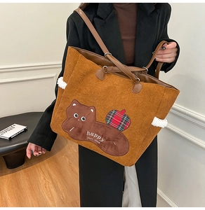 Detail of brown corduroy tote bag featuring bear embroidery and soft leather handles