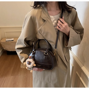 Detail of dark brown leather handbag with vintage gold logo and plush charm accessory