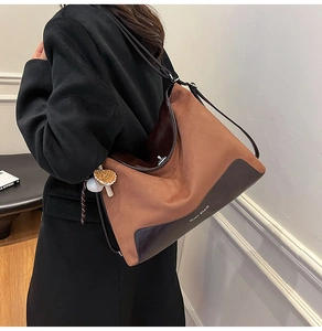 Detail of suede and leather tote bag featuring brand logo and baseball glove charm