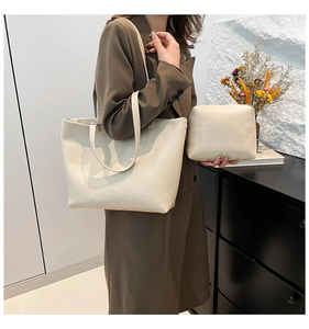 Detail view of cream white faux leather tote bag with matching pouch on indoor background
