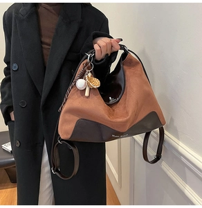 Detail of caramel suede tote bag with smooth leather trim and baseball charm accessory