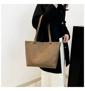Close-up of brown litchi pattern leather tote bag with soft shoulder straps on model