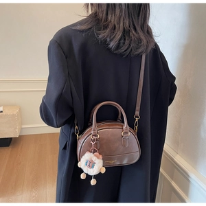 Detail of vintage brown shell handbag with detachable strap and sheep charm accessory