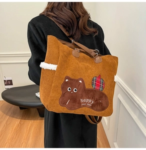 Detail of corduroy tote bag with cat applique and leather handles for women