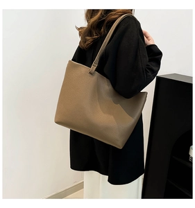 Detail view of a large brown tote bag with premium pebbled leather texture on model