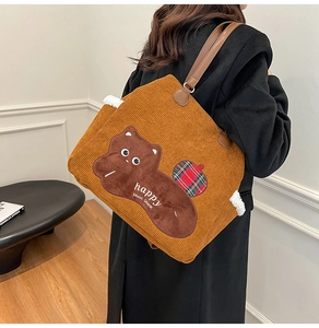 Close-up of brown corduroy tote bag with cartoon plush patch and leather shoulder straps