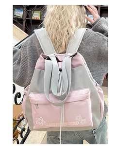 Back view of pink and gray nylon tote backpack worn by a model in a library