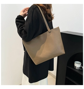 Detailed side view of a large brown leather tote bag worn over the shoulder by a model