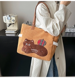 Detail of ginger corduroy tote bag with cartoon embroidery and brown leather handles