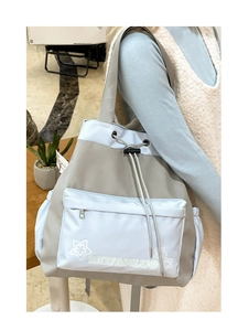 Detail of a blue nylon tote bag with drawstring closure and white star pattern on the front pocket