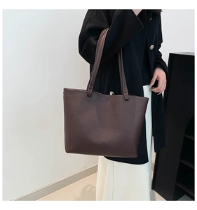 Detailed close-up of a dark brown leather tote bag with elegant gold buckle and shoulder strap