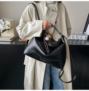 Detail of black large capacity hobo tote with baseball glove charm and leather texture