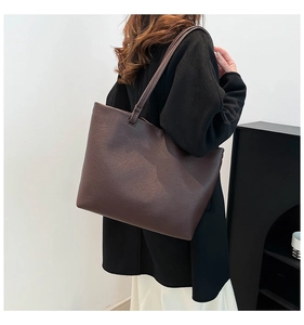 Detail of dark brown tote bag in pebbled leather texture with slim shoulder straps