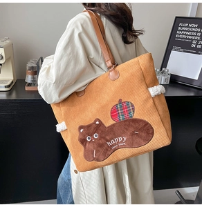 Detail of ginger corduroy tote bag featuring cat embroidery and brown leather straps