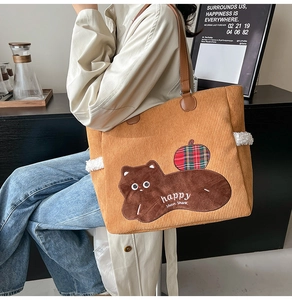 Close-up of brown corduroy tote bag featuring bear embroidery and soft white plush accents