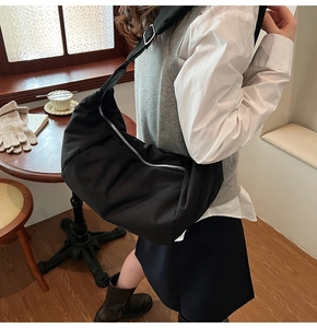 Detailed view of the black oversized padded moon bag worn cross-body in a cozy cafe