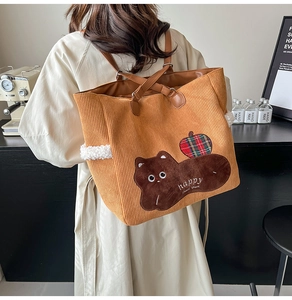 Detail of orange corduroy tote bag with cartoon embroidery and brown leather straps