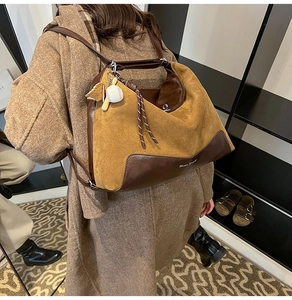 Detail view of large brown leather tote bag with stylish charms and shoulder strap
