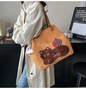 Detailed view of brown corduroy tote bag with bear embroidery and leather straps