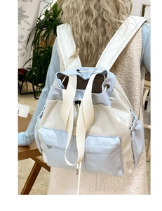 Detail of light blue and beige drawstring backpack with large zipper pocket for daily use