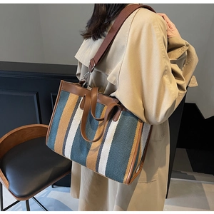 Detailed view of the multi-color striped canvas tote bag with brown leather handles and strap