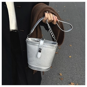 Detail of silver bucket bag with litchi grain leather texture and metallic buckle