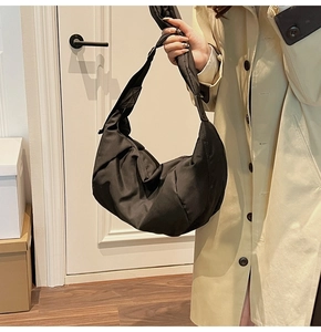 Detail of a black nylon hobo bag with large capacity and knotted shoulder strap design