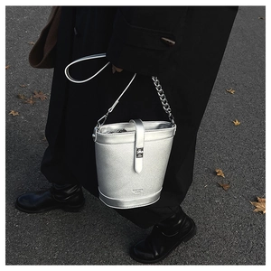 Detail of silver bucket bag in pebble leather with metallic chain strap and buckle closure