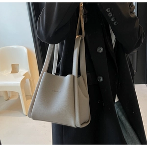 Detail of light gray bucket bag with lychee grain leather texture and double handles