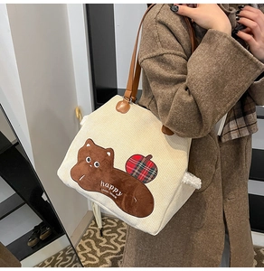 Detail of corduroy tote bag with bear embroidery and brown leather shoulder straps