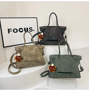 Detailed view of vintage matte tote bags in green, khaki, and grey with plush charms