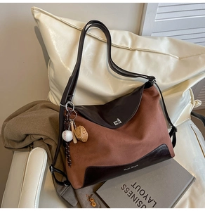 Detail of suede tote bag featuring silver twist lock and baseball themed pendant accessory