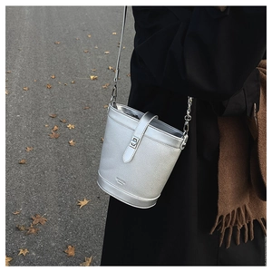 Detail view of silver bucket bag featuring litchi grain leather and metallic chain strap