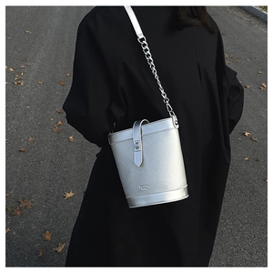 Detail view of silver bucket bag with metallic texture, chain strap, and embossed logo